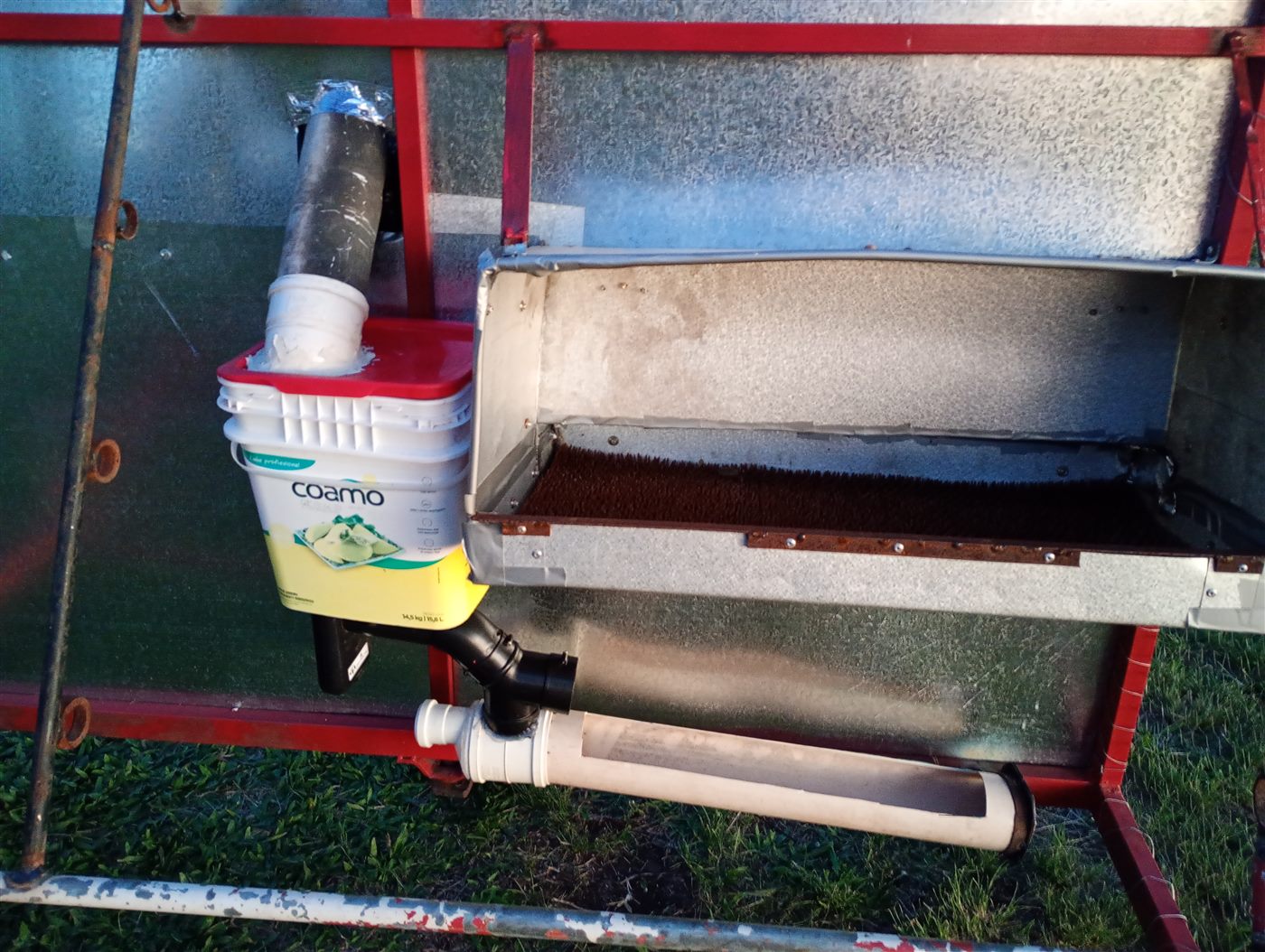 Comedouro automático improvisado com balde e cano de PVC, acoplado à lateral do galinheiro