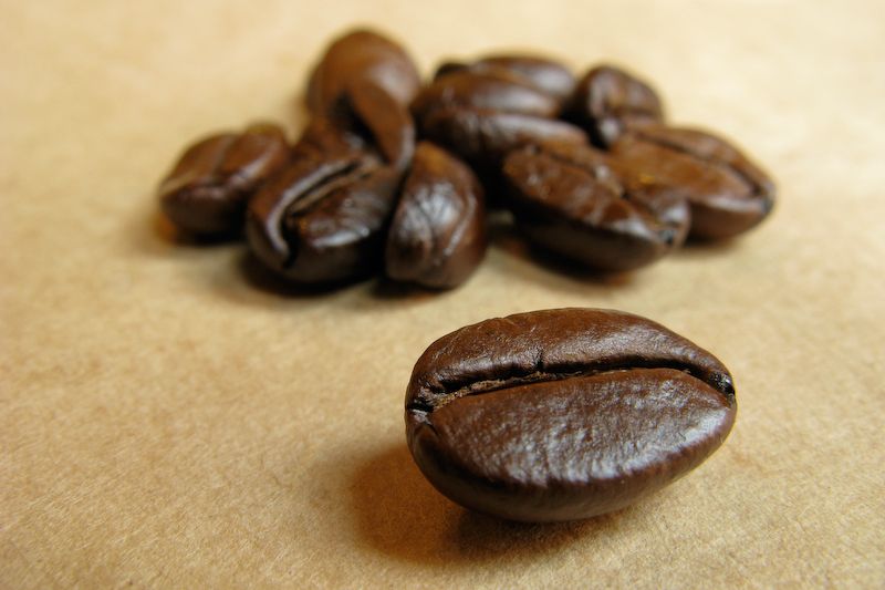 Grãos de café torrados em close, sobre superfície de papel kraft