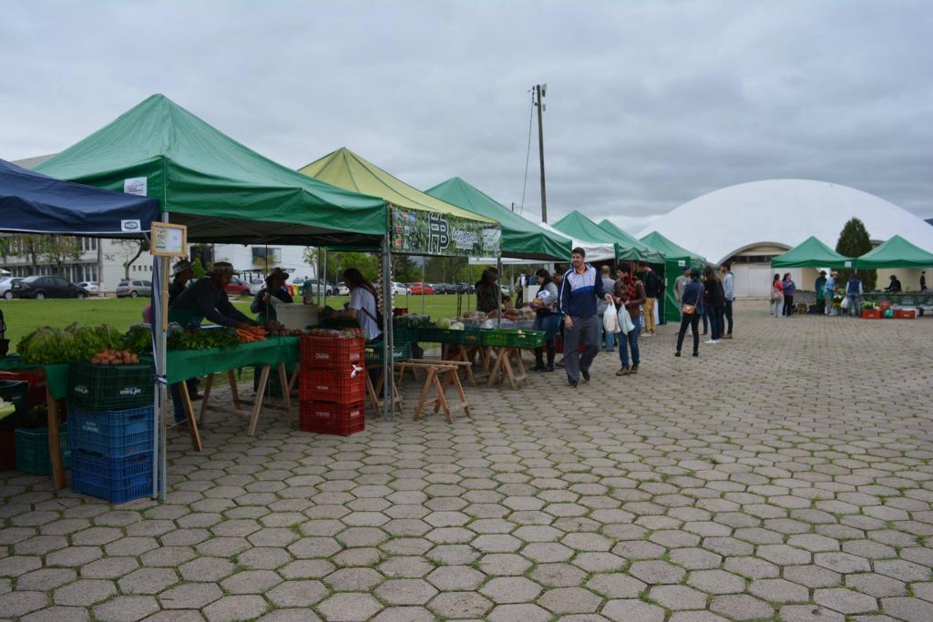 Barracas da Polifeira do Agricultor no campus da UFSM em Santa Maria, com produtores vendendo diretamente aos consumidores